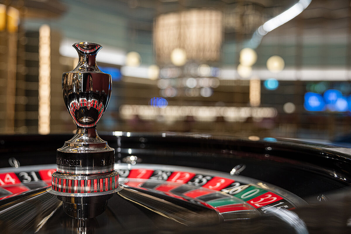 Nahaufnahme eines Rouletterads in einem Casino mit glänzender schwarz-roter Oberfläche. Der Hintergrund zeigt verschwommene Lichter, die ein elegantes Ambiente schaffen.