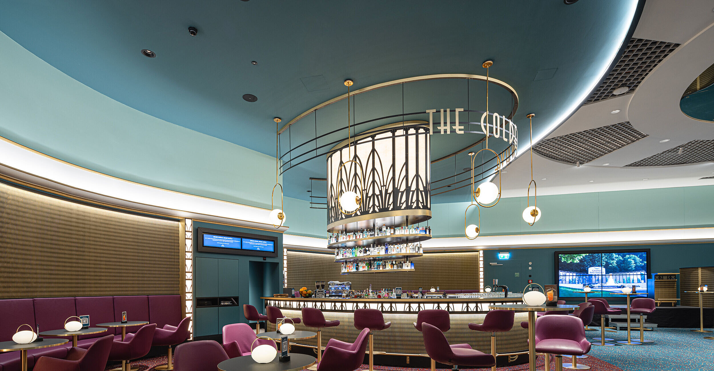 Modernes Bar-Interieur im retro-futuristischen Design: Lila Stühle, runde Tische und hängende Kugelleuchten schaffen eine stilvolle, einladende Atmosphäre.