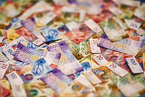  Eine bunte Auswahl an Schweizer Franken-Banknoten, zufällig verstreut. Die Banknoten weisen unterschiedliche Nennwerte und lebendige Designs auf und vermitteln Reichtum und Vielfalt.